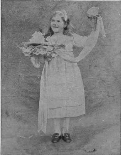 The little daughter of the house distributing favours of paper roses from a ribbon decked basket at a St. Valentine's Day party