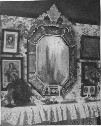 A beautiful modern Venetian mirror of antique design, placed above the mantelpiece of a small, low room