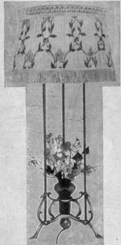 A standard flower lamp for the centre of a dining table. The lighting is given by three concealed bulbs under a pretty shade. The lamp is arranged so as not to obscure the view of the guests