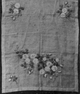 Shaded rose pink ribbon worked into blossoms and buds on white muslin. The stems are embroidered, the leaves of ribbon