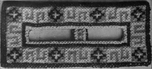 A hat buckle worked in cross stitch, mounted on canvas. The centre strap should be worked separately and slipped between the canvas and the lining