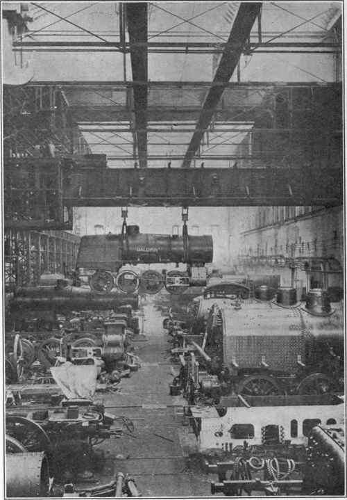 Locomotive Building View in the erecting shop where the locomotives are assembled. The traveling crane in the foreground is capable of transporting a locomotive to any part of the shop.